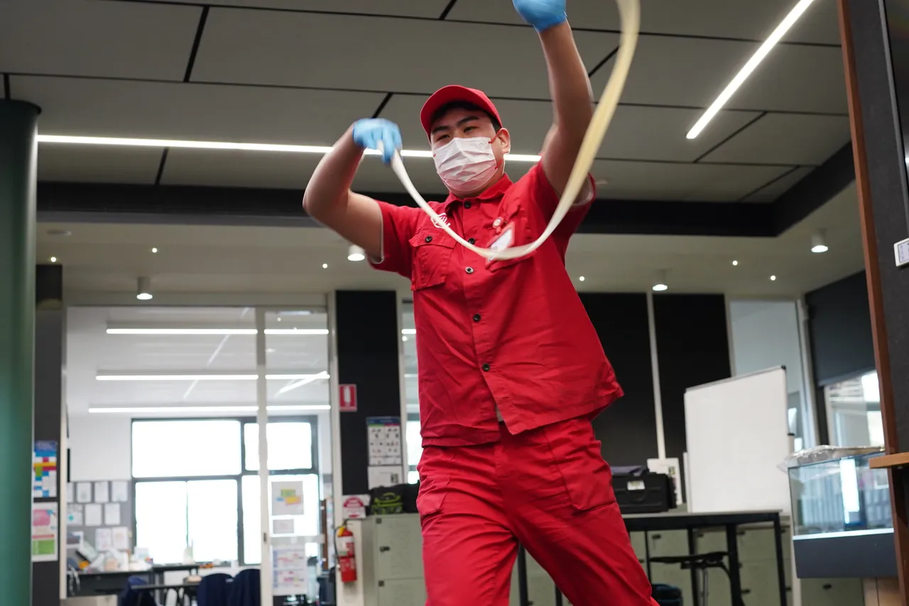 Low angle photo of a professional Chinese noodle maker as he performs a dramatic noodle pulling performance as part of a cultural presentation during Overnewton’s 2025 Languages and Culture Week.