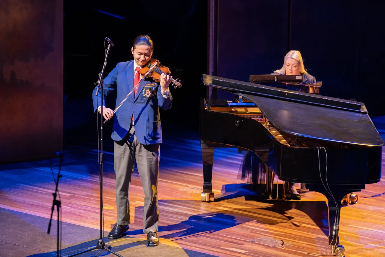 Upper secondary school aged student from Overnewton Senior School playing violin on stage at Hamer Hall, accompanied by piano during the 2025 Presentation Night.