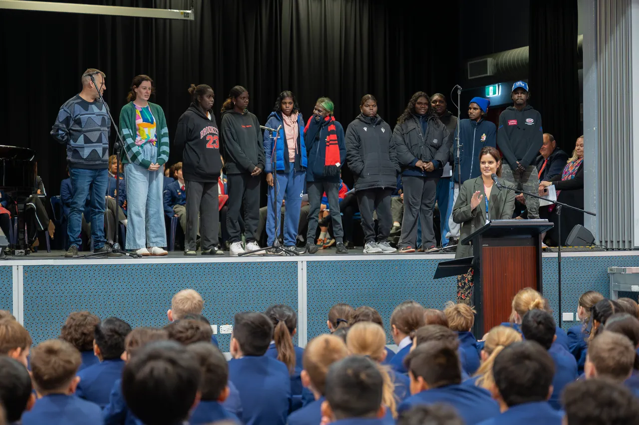 Upper secondary school-aged students from Overnewton Anglican Community College's sister (yapa) school in East Arnhem Land, Northern Territory, Shepherson College, standing on stage as part of the 2025 Yirramboi Campus Reconciliation Week Assembly.