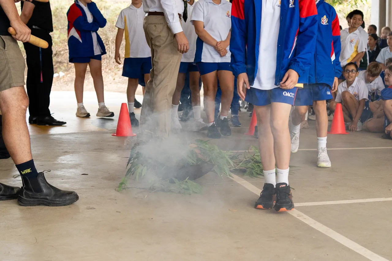 Year 5 students ceremoniously walking through the cleansing smoke of eucalyptus leaves as part of an annual Smoking Ceremony for Year 5 students new to the Yirramboi Campus.