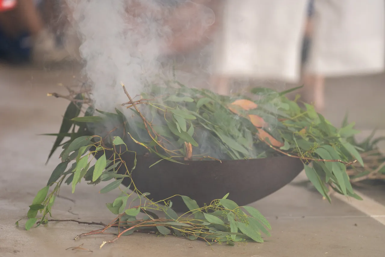 Close up of a lit fire pit filled with eucalyptus leaves, giving off plumes of cleansing smoke as part of an annual traditional Smoking Ceremony for Year 5 students new to the Yirramboi Campus.