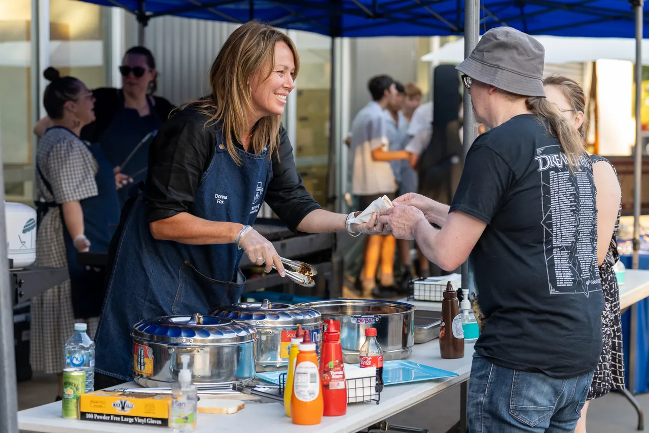 Member of Overnewton College Leadership Team serving a community member at the sausage sizzle during the inaugural Yirramboi Parent Information Evening.