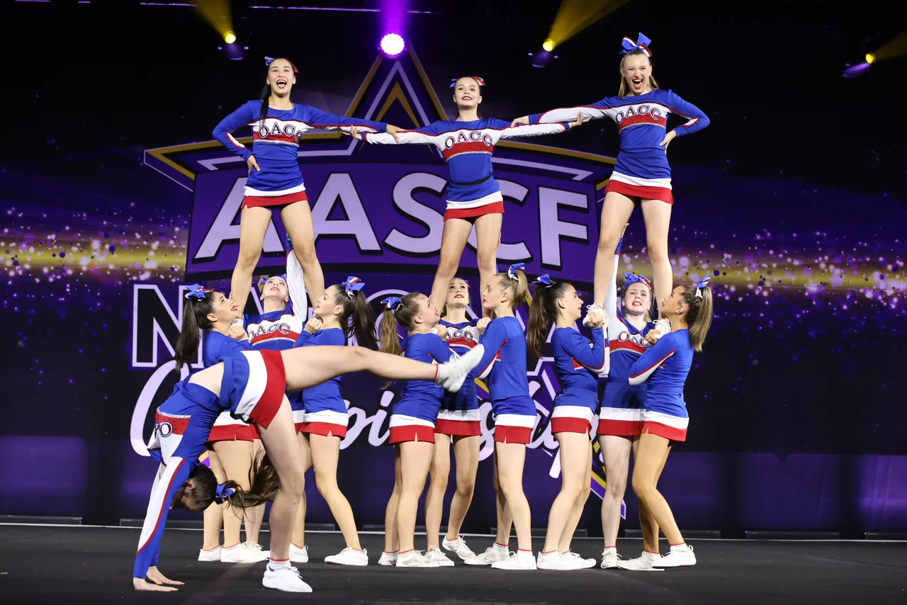 Action shot of the award-winning Overnewton cheer team performing stunts in official cheer uniforms during competition.