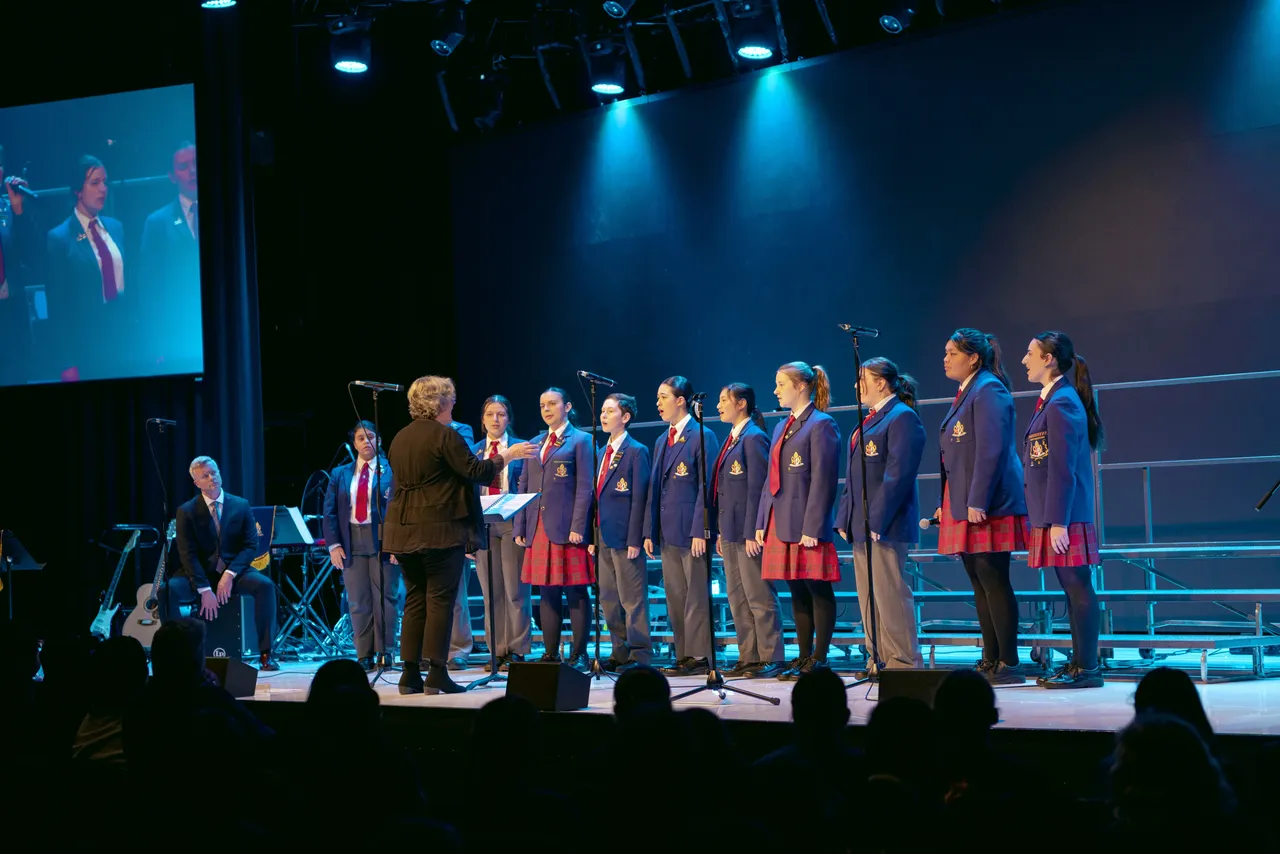 Group of middle and upper secondary school aged students performing on stage as part a choir at Overnewton’s annual Festival of Music, the signature event of the Encore Performing Arts Co Curricular program.