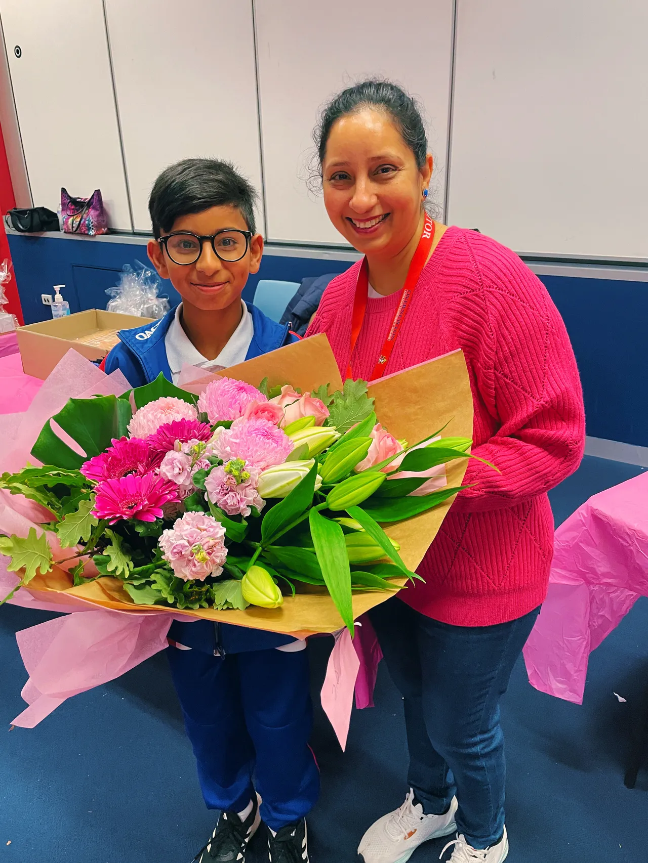 Parent volunteer with her son, smiling after receiving a large bunch of beautiful flowers.