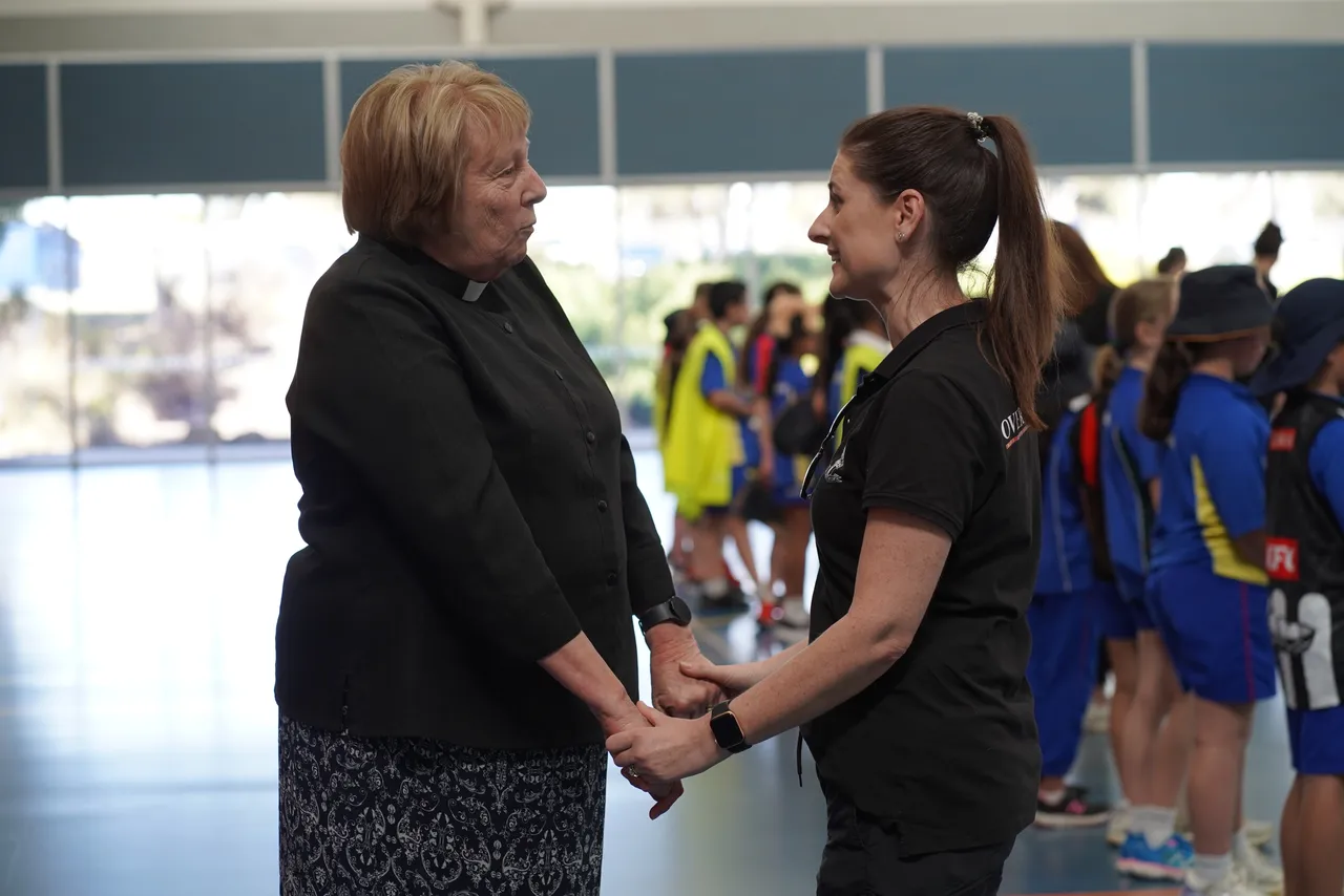 Reverend Carmel Hunter in conversation with an Overnewton staff member, holding hands in a warm and respectful exchange.