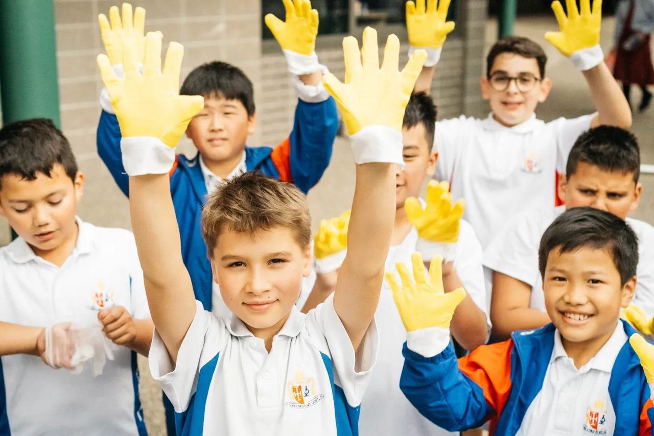 Upper primary school aged students proudly showing their rubber gloves after picking up rubbish at Yirramboi Campus as part of the sustainability program.