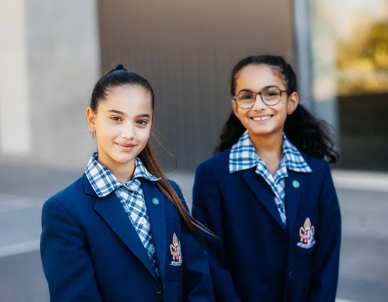 Two upper primary school aged girls in impeccable school uniform, smiling and posing at Yirramboi Campus.