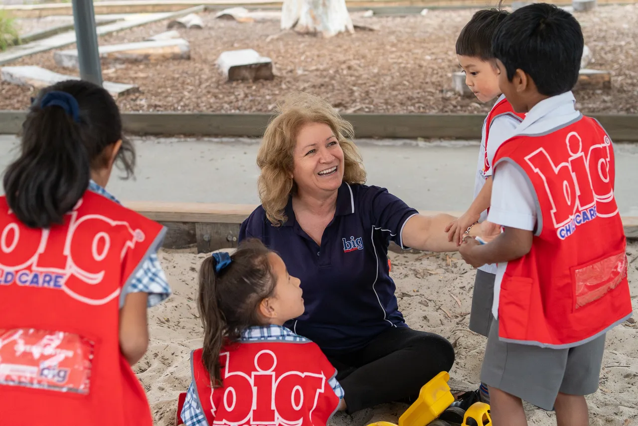 Big Child care staff member with a lower primary school aged student playing in the sandpit at Canowindra Campus, after school.