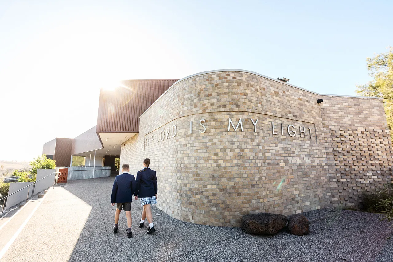 Upper primary school students enjoying time outside the Middle School building at Yirramboi Campus, with “The Lord is My Light” inscribed on the wall.