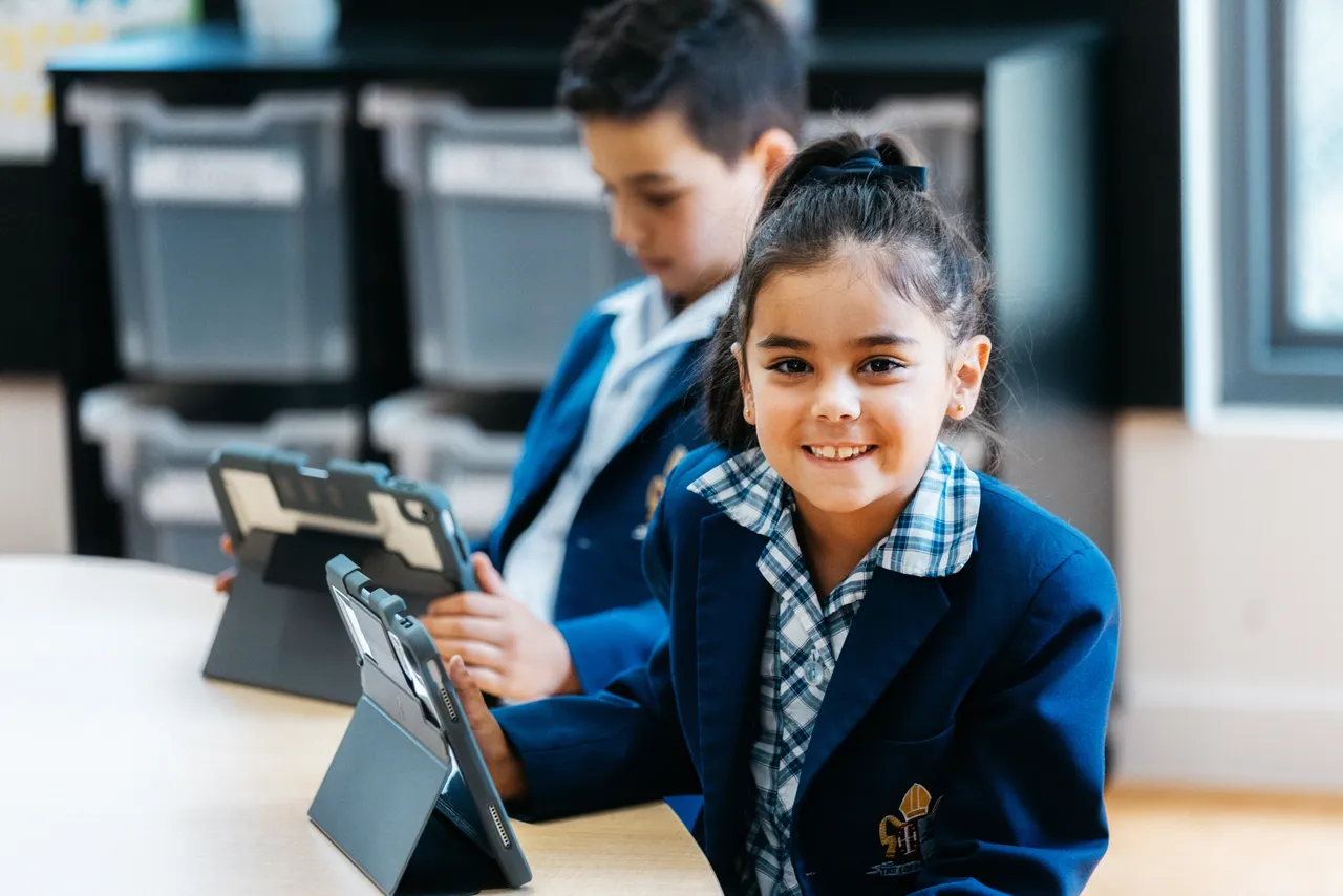 Lower primary school aged girl looking at the camera while using an iPad at Canowindra Campus.