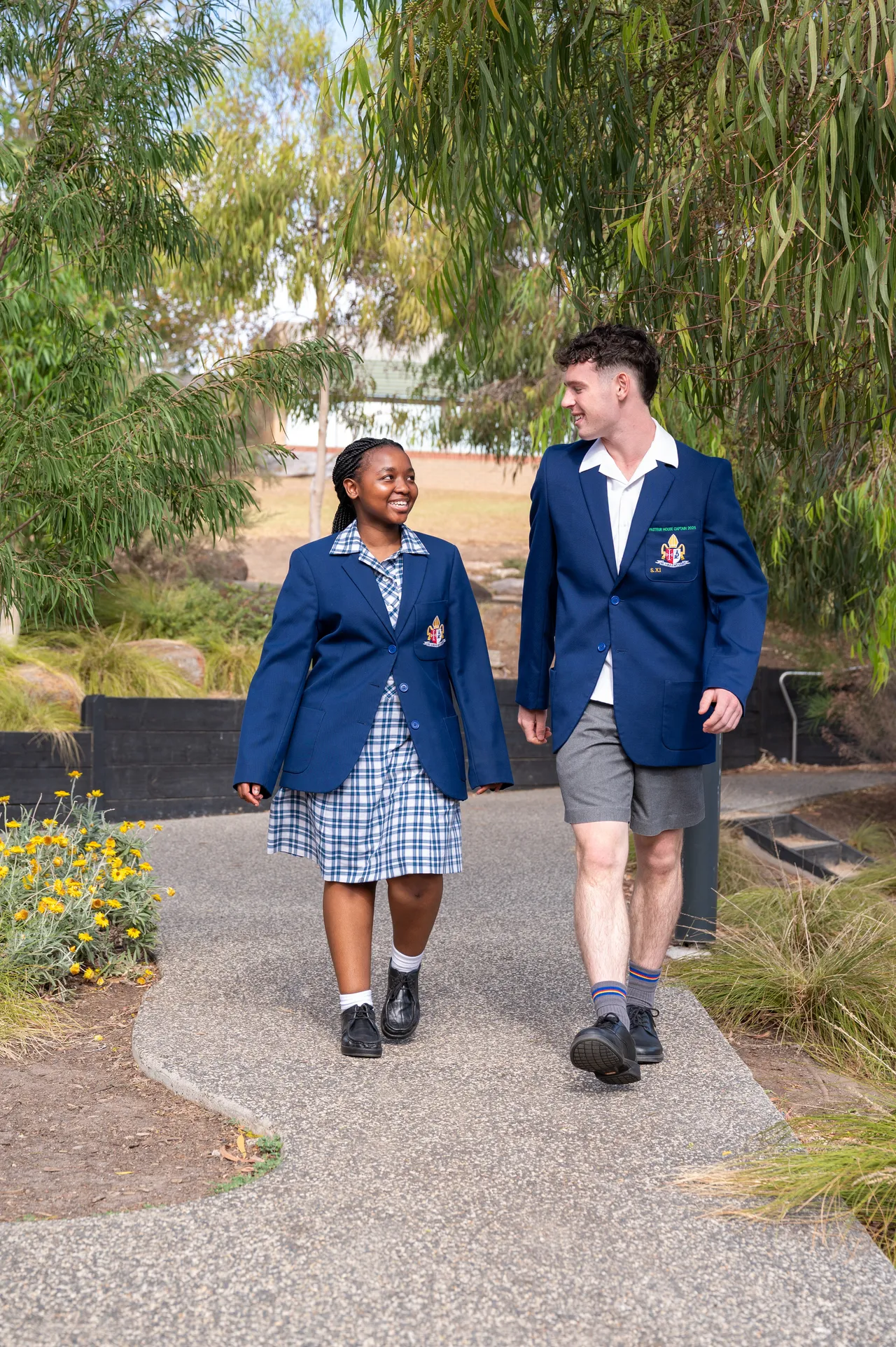 Two upper high school aged student in impeccable school uniform, smiling and posing at Yirramboi Campus.