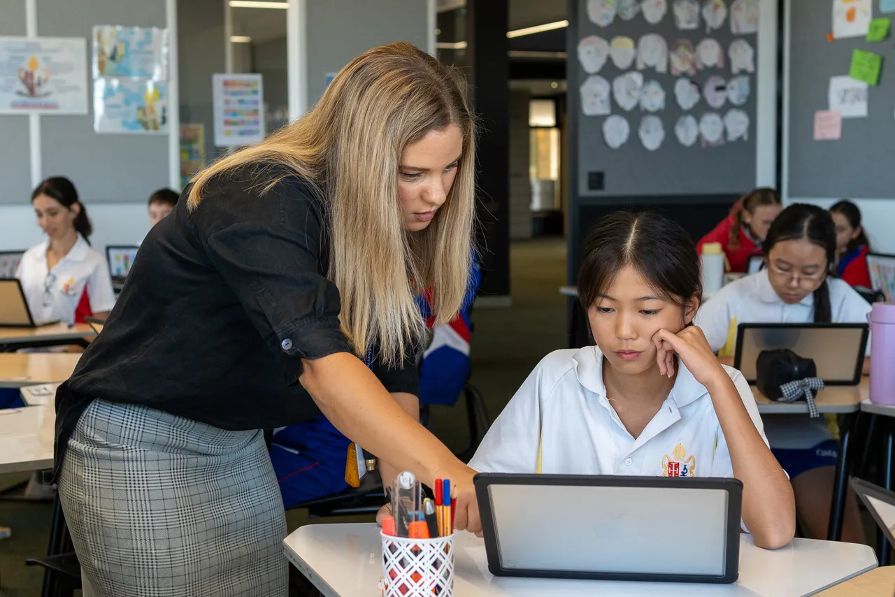 Teacher working with a student using a laptop in a Middle School class at Yirramboi Campus