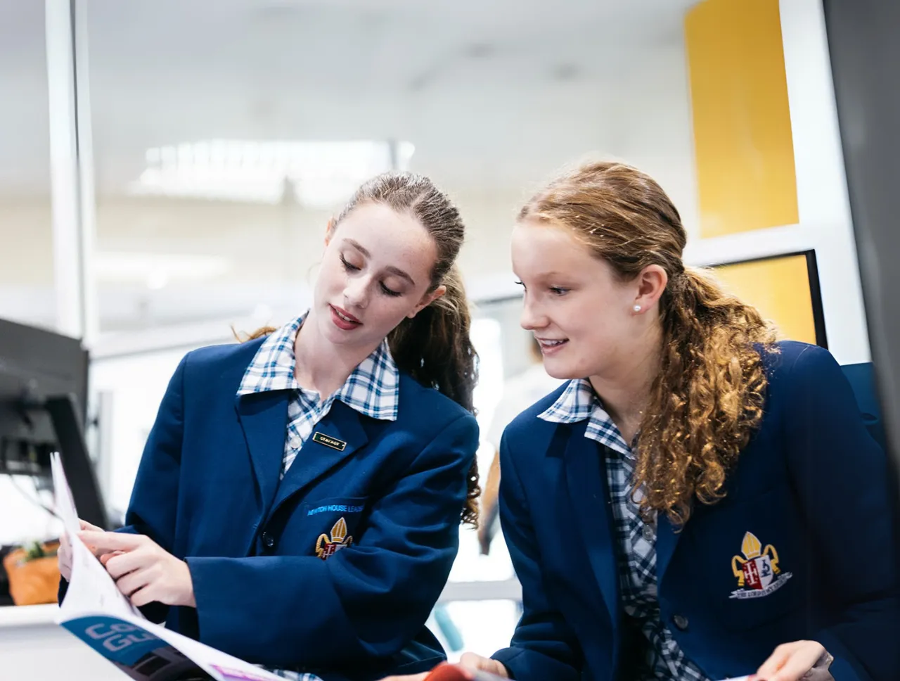 Two upper high school aged girls reading a document together and studying at Yirramboi Campus