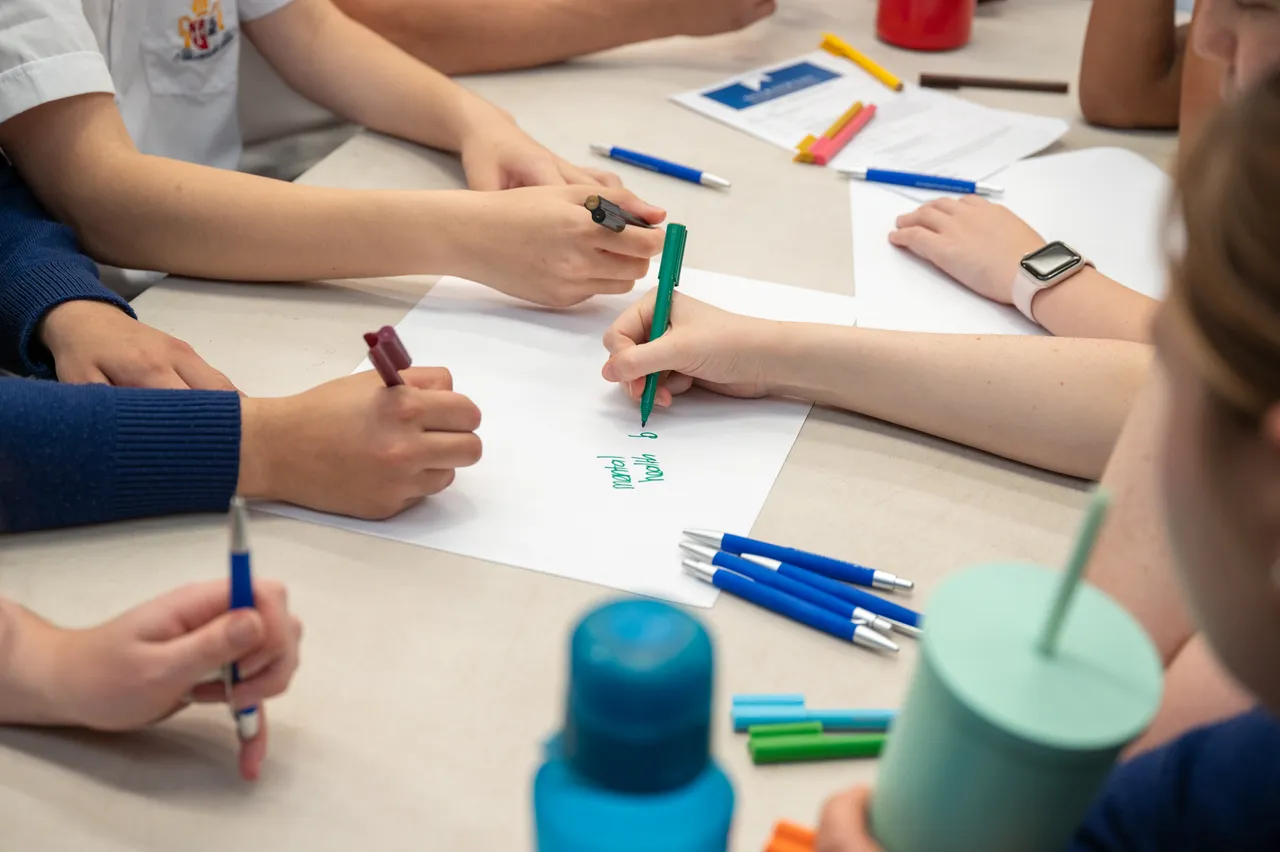 Upper secondary school aged students holding pens as work collaboratively on a team building exercise during Overnewton's second Student Leadership Summit.