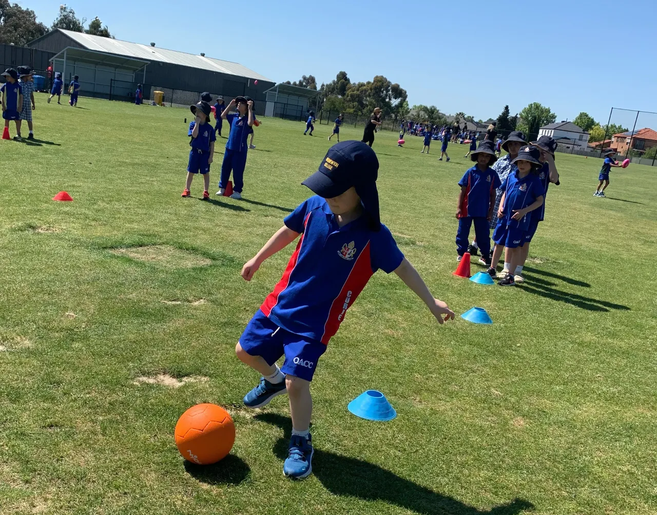 Lower primary school aged students developing gross motor skills by kicking balls through obstacles during a House Activate Day, part of Overnewton’s extensive co-curricular program.
