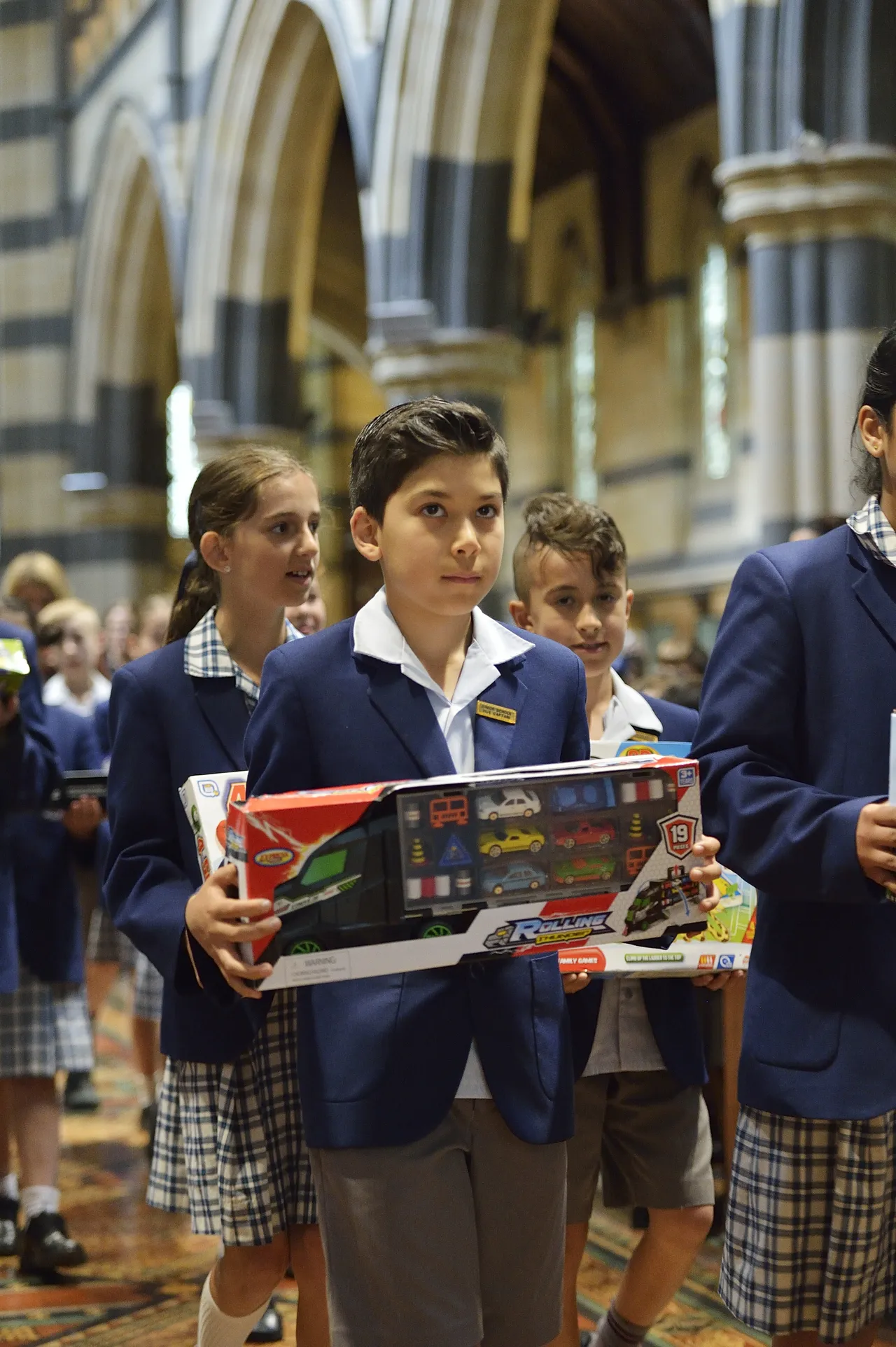 Primary school aged students donating toys to Anglicare at St Paul’s Cathedral during Overnewton’s annual Carols Service, demonstrating the school’s commitment to service learning and community giving.