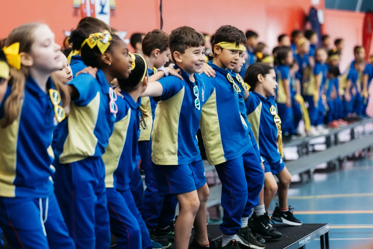 Primary school aged student performing with peers as part of Edison House (yellow) at Overnewton during the Encore House performance, where all students come together to perform for each other.