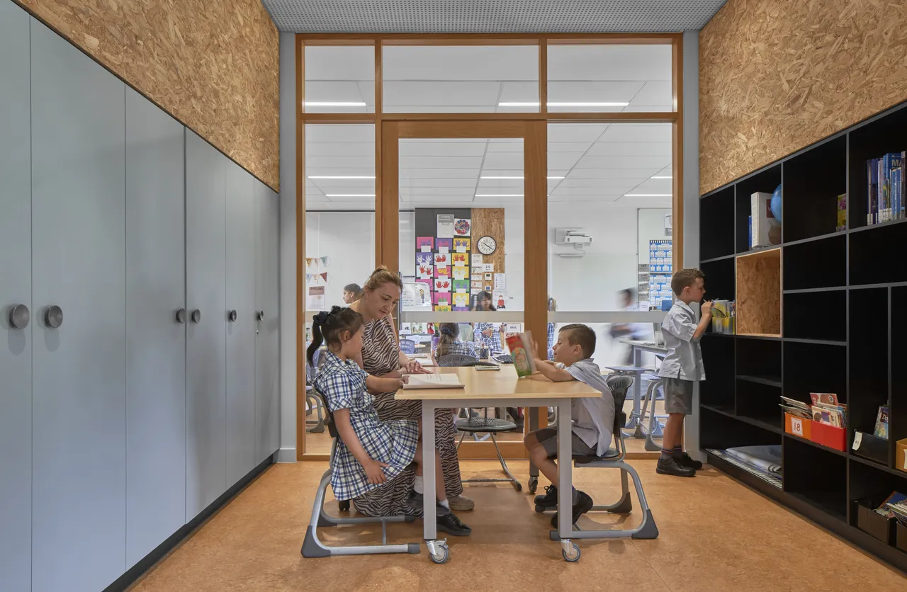 Small group learning session with a staff member and three lower primary school aged students in a quiet breakout area inside the Prep to Year 2 building at Canowindra Campus.