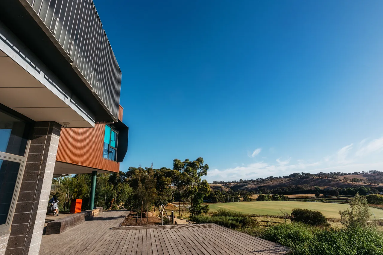 Side view of the award-winning Middle School building at Yirramboi Campus under a clear blue sky, overlooking the sports field and the Keilor Valley.