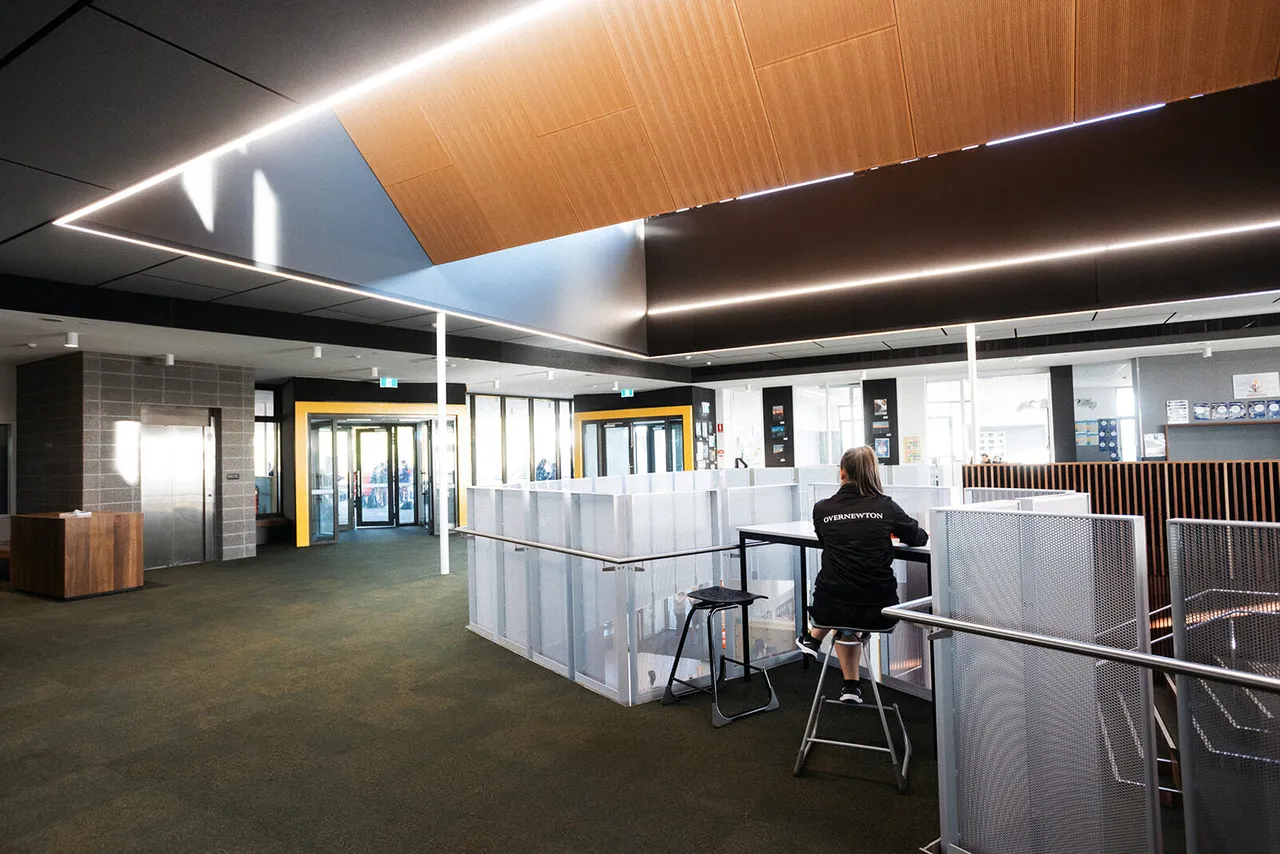 Teacher seated in the open-plan interior of the award-winning Middle School building at Yirramboi Campus, beneath an architecturally designed roof.