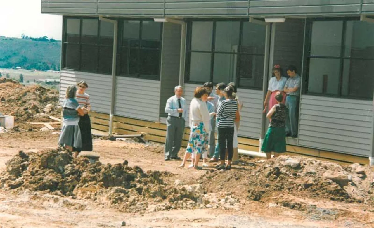 Archival photo from 1987 of Buck Brooksbank leading a teacher tour at Overnewton’s Keilor Campus, with school portables, rocks, and dirt visible in the foreground—highlighting the early, rugged beginnings of the school.
