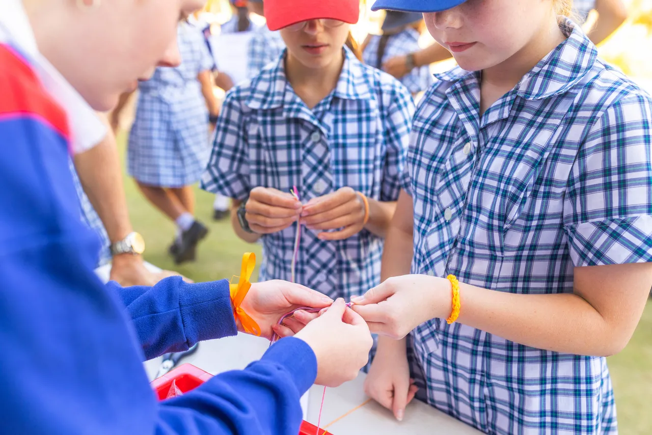 Middle School student exchanging orange friendship bracelets with a peer as part of Harmony Day celebrations at Overnewton, symbolising inclusion and connection.