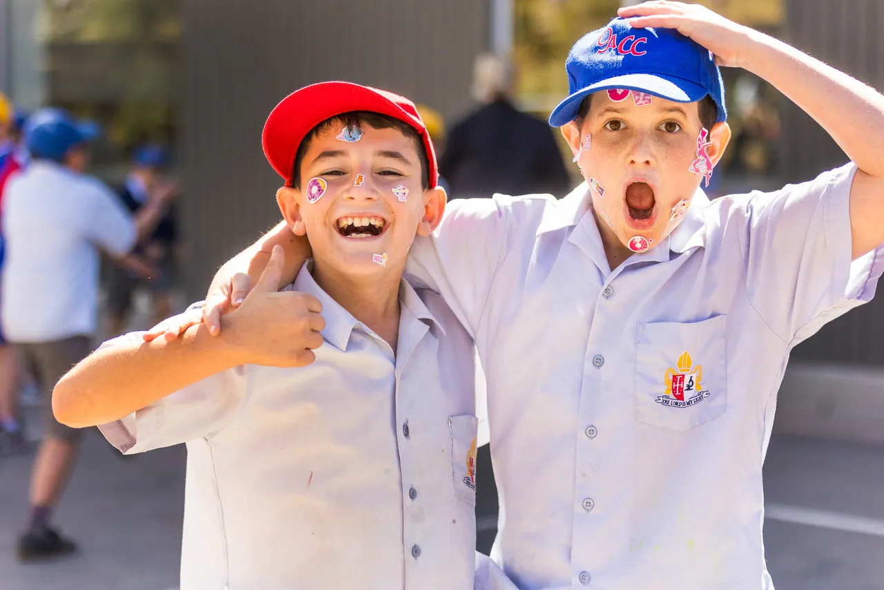 Two lower secondary school aged students standing together, one with an arm around another, having fun during Overnewton Middle School's Harmony Day celebrations.