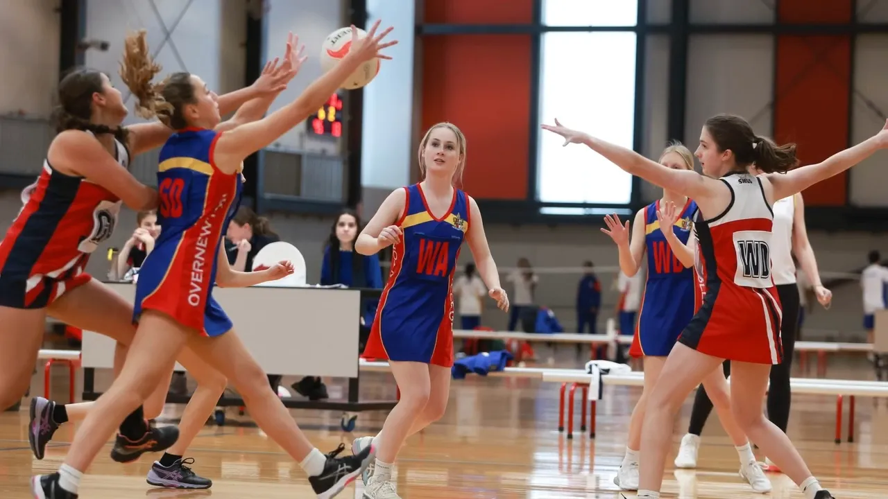 Overnewton student in action catching a netball during a competitive game against another school, showcasing skill and teamwork on the court.
