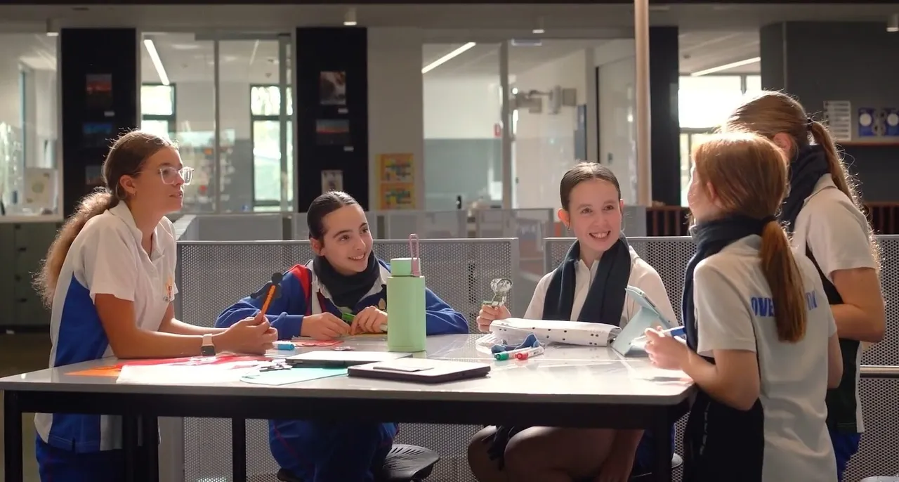 Lower high school aged students sitting at high tables in the open learning space of the award-winning Middle School building at Yirramboi Campus, actively engaged in learning and discussion.