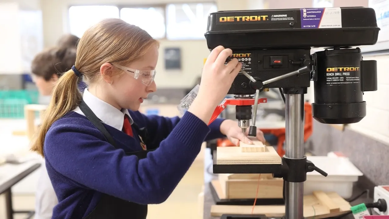 Upper primary school aged student using a drill press during her Technologies class in the Middle School at Yirramboi Campus, working confidently on a woodwork project.