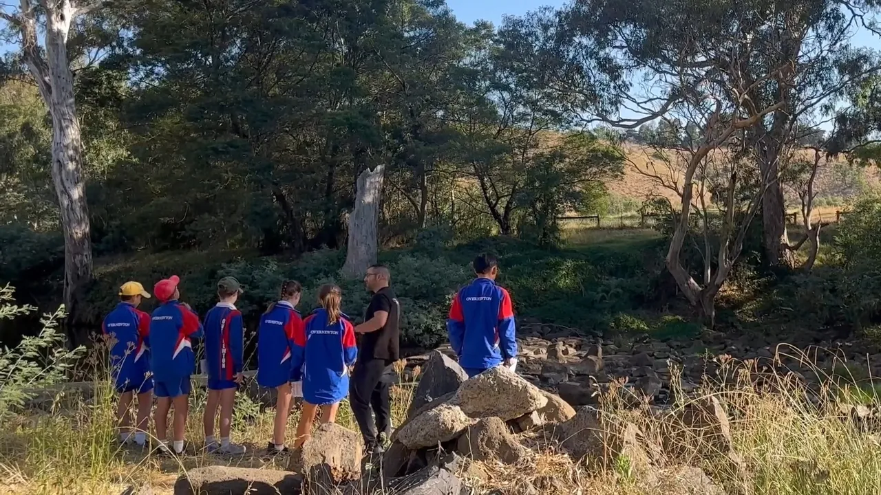Groups of students exploring the native Australian bush at Yirramboi Campus, learning about the environment with a teacher among trees, rocks, shrubs, and natural surroundings.