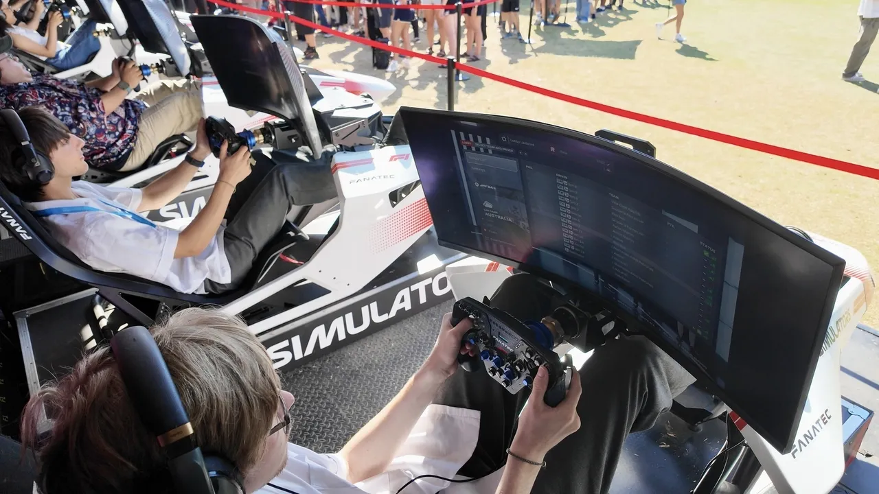 Two Overnewton senior secondary school aged VCE Vocational Major students experiencing a Formula 1 drive simulator, part of an interactive Driving Learning educational exhibit at the Melbourne Formula 1 Grand Prix.