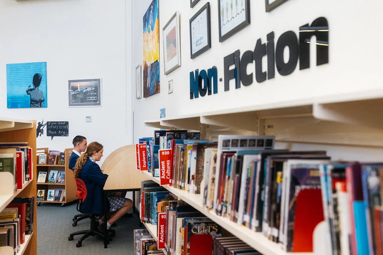 Two senior secondary school aged students seated at study desks in the spacious, light-filled Senior School Library at Overnewton’s Yirramboi Campus, Keilor.
