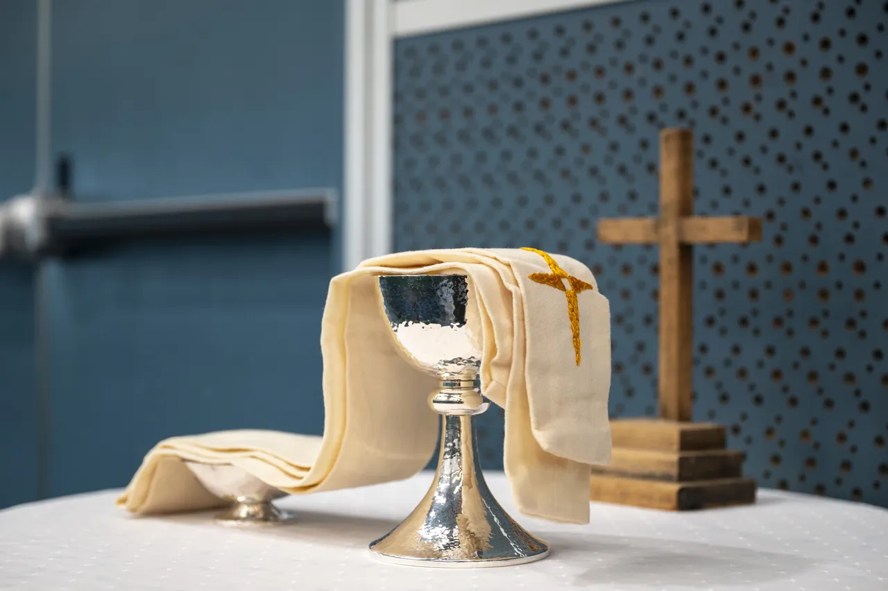Anglican chalice with a stole draped over the top, prepared for the Eucharist, with a cross visible in the background—capturing a sacred moment of worship and tradition at Overnewton.