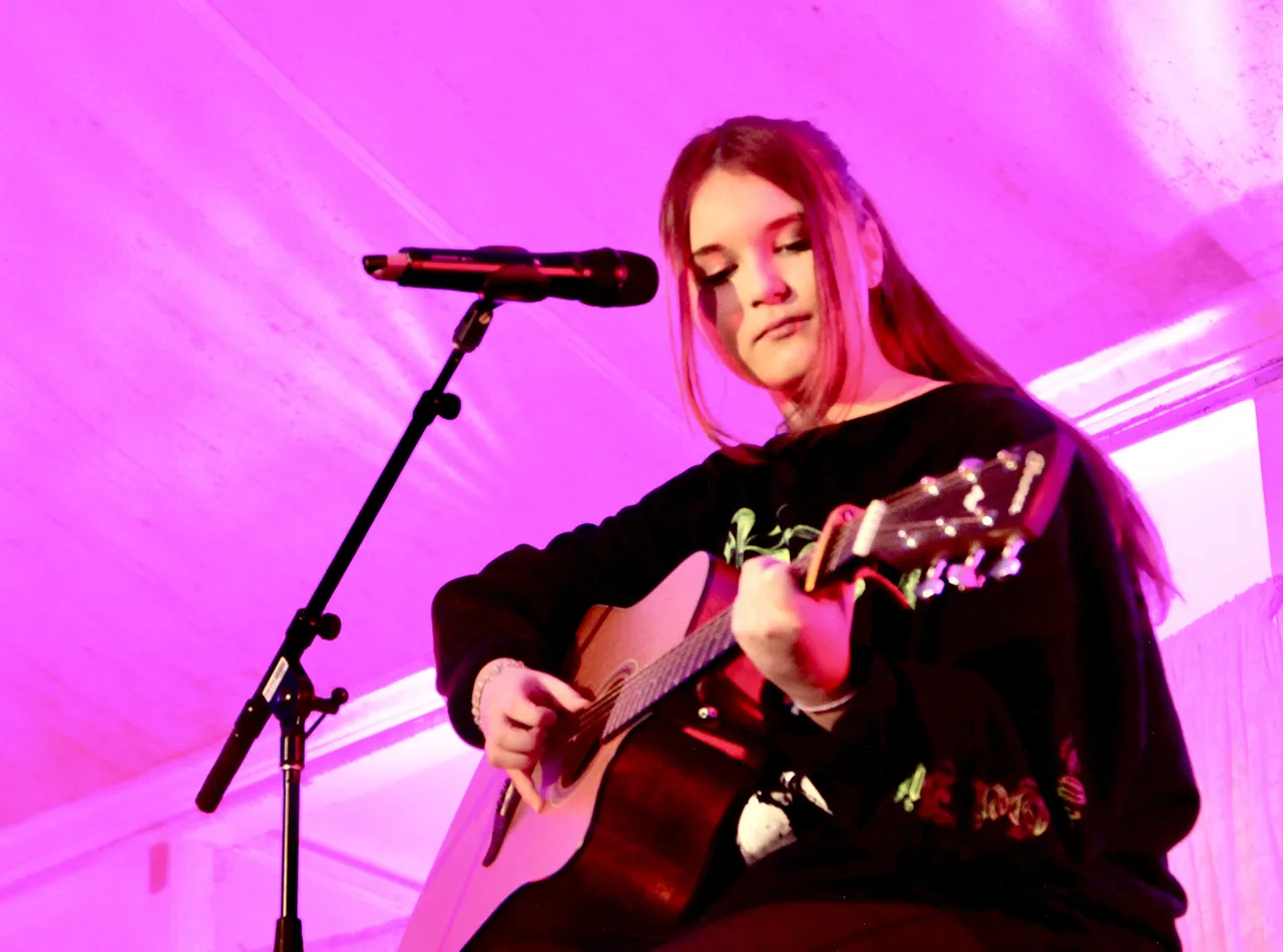 Middle secondary school aged student performing a song on guitar on a brightly lit stage during 'Out of the Blue' at Overnewton’s annual Festival of Music, the signature event of the Encore Performing Arts Co Curricular program.