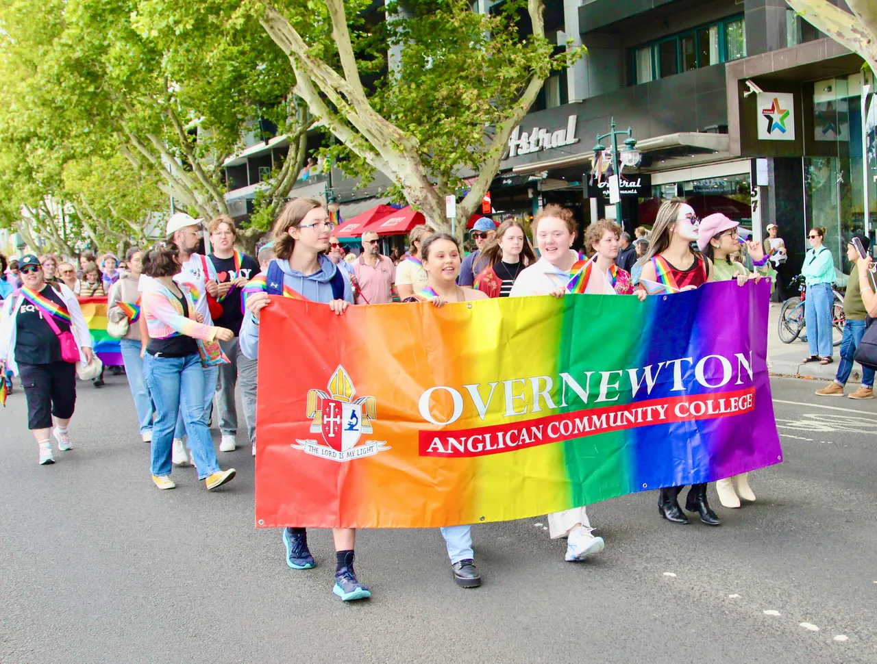 A group of upper secondary school aged students and staff representing Overnewton Anglican Community College at the 2026 Midsumma Pride March, proudly holding our rainbow College banner as they parade down Fitzroy Street, St Kilda.