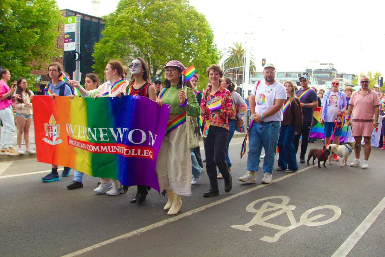A group of upper secondary school aged students and staff representing Overnewton Anglican Community College at the 2026 Midsumma Pride March, proudly holding our rainbow College banner as they parade down Fitzroy Street, St Kilda.
