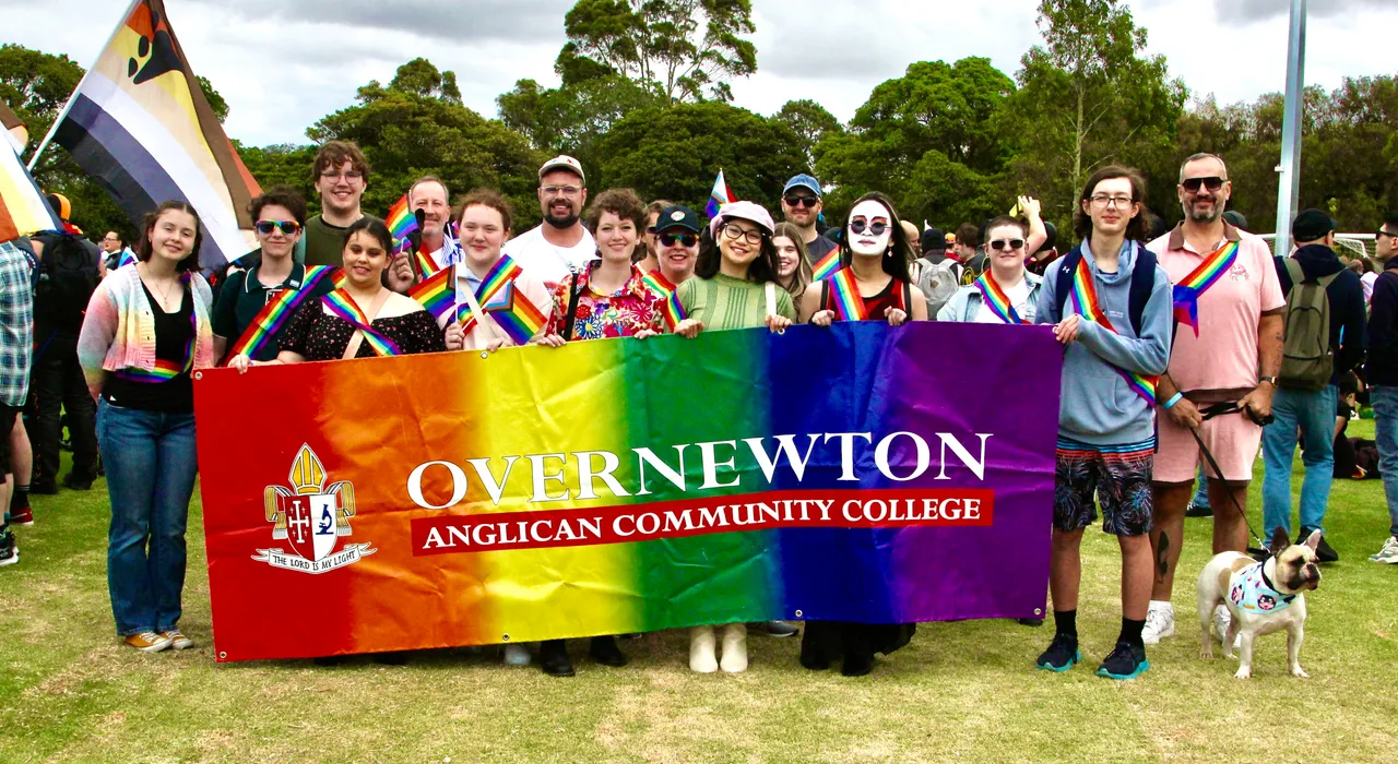 A group of upper secondary school aged students and staff representing Overnewton Anglican Community College at the 2026 Midsumma Pride March.  Group is assembled, proudly holding a rainbow-coloured Overnewton school banner.