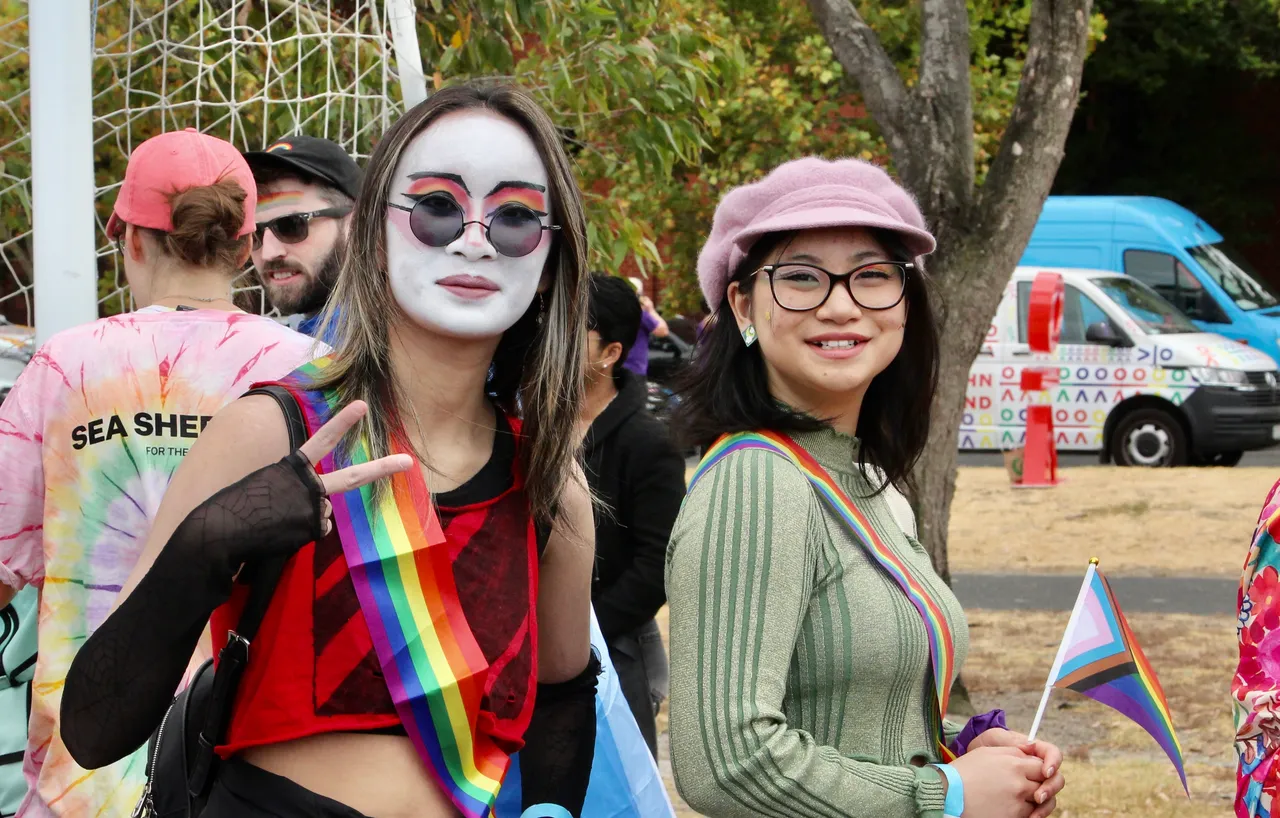 Two upper secondary school aged students proudly representing Overnewton Anglican Community College at the 2026 Midsumma Pride March, holding rainbow flags and wearing colourful face paint.