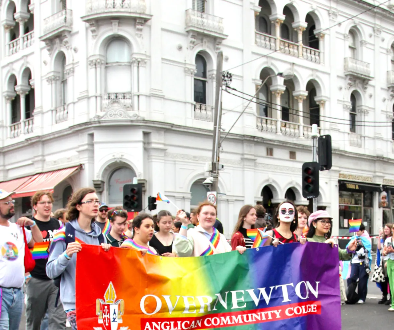 A group of upper secondary school aged students and staff representing Overnewton Anglican Community College at the 2026 Midsumma Pride March.  Students can be seen walking in front of the iconic facade of the Prince of Wales Hotel in St Kilda.