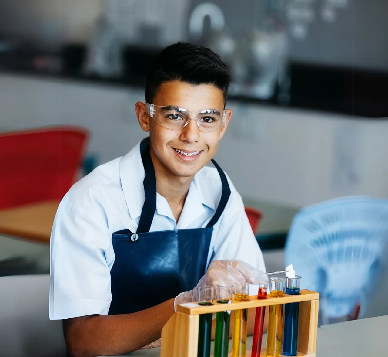 Year 9 student in a science laboratory completing an experiment while looking to camera