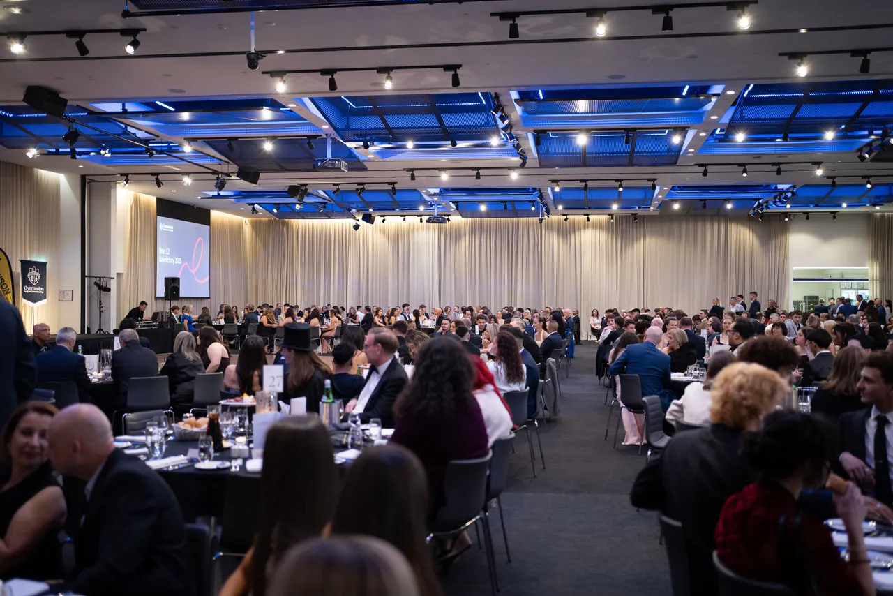 A wide angle photo of dozens of tables with upper secondary students from the Overnewton Class of 2025 and their families, gathering together at their Valedictory Dinner event held at Hyatt Place, Essendon Fields.