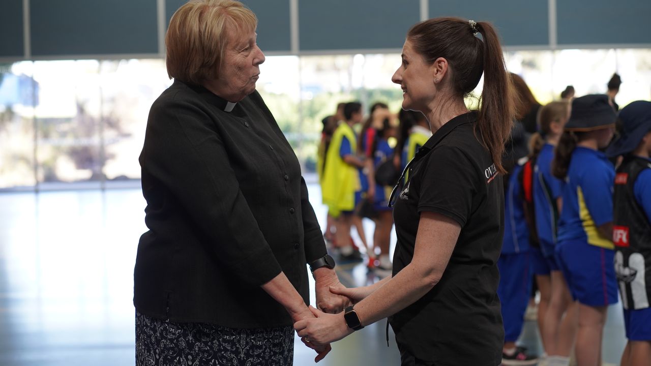 Reverend Carmel Hunter in conversation with an Overnewton staff member, holding hands in a warm and respectful exchange.