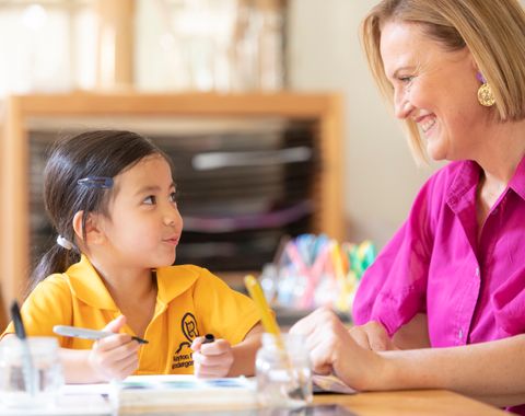 A kindergarten student smiling at her teacher in the Early Learning Centre at Ruyton Girls' School