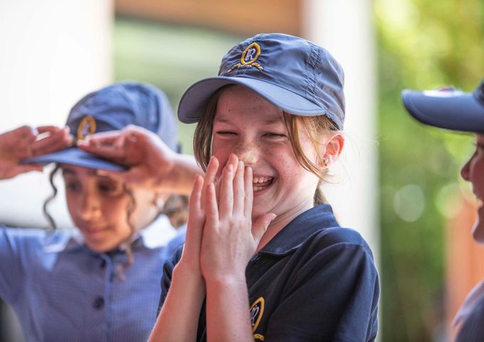 A Junior School student from Ruyton Girls' School laughing with her friends. She is wearing PE uniform in House colours.