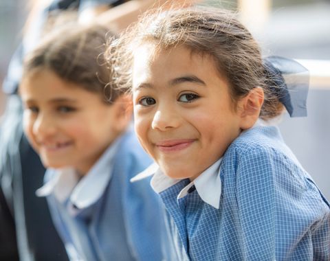 A Junior School student at Ruyton Girls' School smiling in the playground.