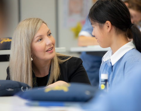 Junior School teacher engaging one on one with a student in a classroom setting.