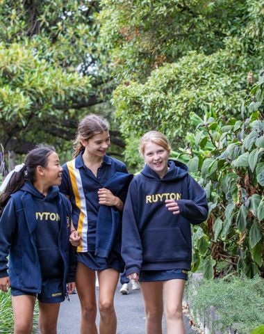 Senior School students smiling at each other as they walk down a garden path.