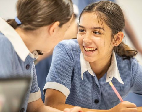 Two students talking and laughing together in the classroom
